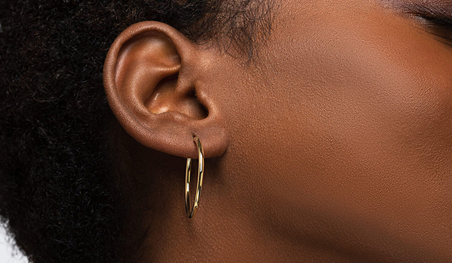 A woman wearing a Birks Essentials gold hoop earrings.